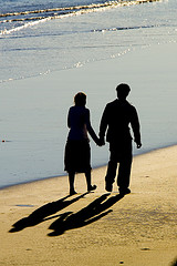 Two people walk holding hands